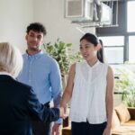 Frais d'agence immobiliere en Belgique : agent immobilier serrant la main d'un couple / Makelaarskosten in Belgie: vastgoedmakelaar schudt de hand van een koppel